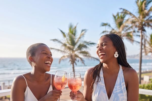 Two friends toasting Tjello spritzes by the sea